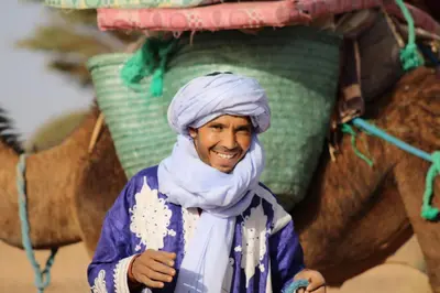 a man wearing a turban standing in front of an elephant at Hassan's Guest House in Mhamid