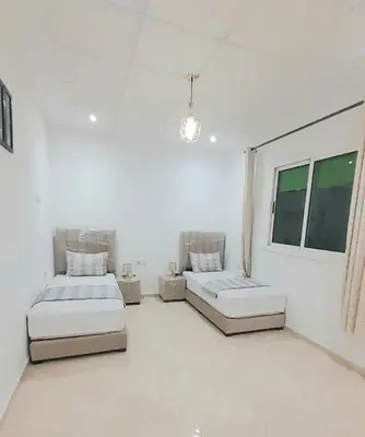 a white room with two beds and a window at City escapade apartement in Fès