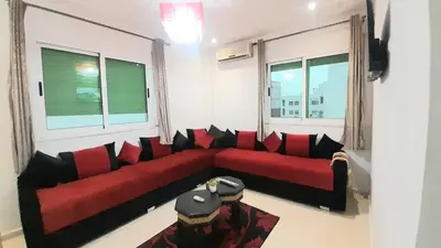 a living room with a red couch and two windows at City escapade apartement in Fès