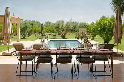 a dining table with chairs and a pool at Salamouni Villa ideal for family, 4-6 chambres, 8-12 personnes in Oulad Snaguia