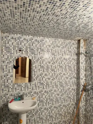 a bathroom with a sink and a mirror on a tiled wall at Appartement calme et spacieuse in Meknès