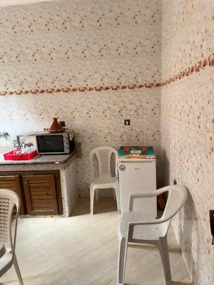 a kitchen with two chairs and a table and a microwave at Appartement calme et spacieuse in Meknès