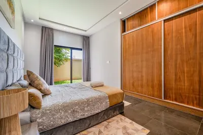 a bedroom with a large bed and a large wooden closet at Red villa, pool not overlooked in Oulad Akkou