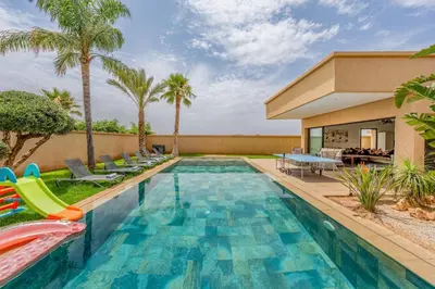 a swimming pool with chairs and a house at Red villa, pool not overlooked in Oulad Akkou