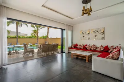 a living room with a red couch and a large window at Red villa, pool not overlooked in Oulad Akkou
