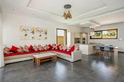 a living room with a red couch and a kitchen at Red villa, pool not overlooked in Oulad Akkou