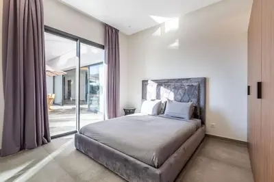 a bedroom with a large bed and sliding glass doors at Luxury villa, private heated pool, jacuzzi, games in Oulad Akkou