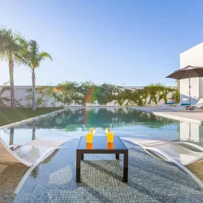two drinks on a table next to a swimming pool at Luxury villa, private heated pool, jacuzzi, games in Oulad Akkou