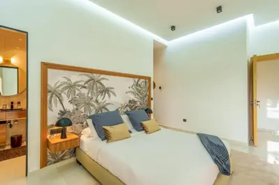 a bedroom with a large white bed with blue pillows at Villa Belkis, games, Hammam, swimming pool, not overlooked in Oulad Akkou