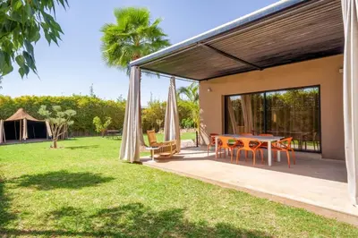 a patio of a house with a table and chairs at Villa Belkis, games, Hammam, swimming pool, not overlooked in Oulad Akkou