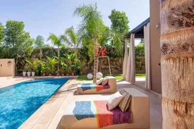 a swimming pool with two chaise lounges next to a house at Villa Belkis, games, Hammam, swimming pool, not overlooked in Oulad Akkou