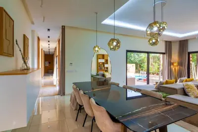 a dining room with a glass table and chairs at Villa Belkis, games, Hammam, swimming pool, not overlooked in Oulad Akkou