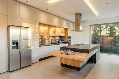 a kitchen with stainless steel refrigerator and a wooden table at New villa k, heated pool, Hammam in Oulad Akkou