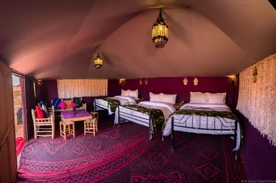 a room with four beds and a table and chairs at The Desert Palace in Merzouga