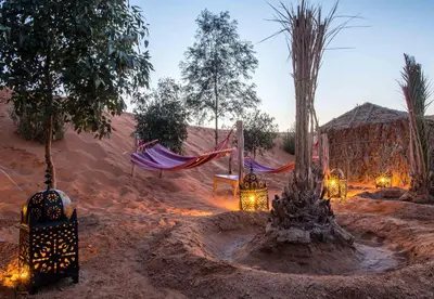 a desert area with a hammock and a tree at The Desert Palace in Merzouga