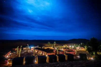 a group of tents in the desert at night at The Desert Palace in Merzouga