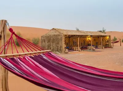 a hammock in front of a hut in the desert at The Desert Palace in Merzouga