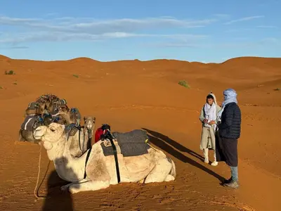 a couple of people and a camel in the desert at lunara camp in Merzouga