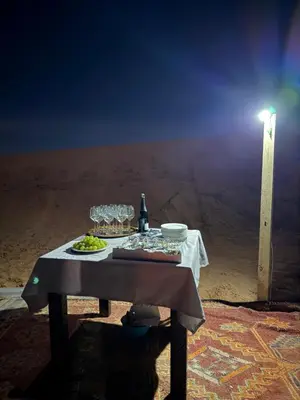 a table with glasses and a bottle of wine at lunara camp in Merzouga