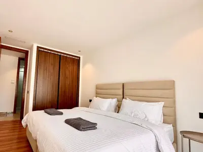 a bedroom with a large white bed with two towels on it at Cocon Elégant CFC, Pool, Gym & Parking Gratuit in Oulad Akkou