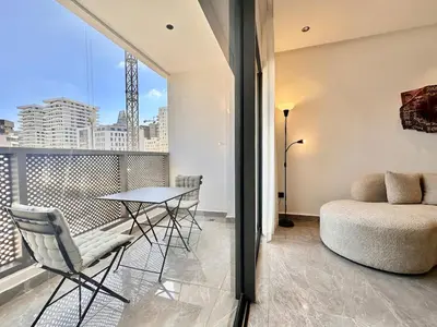a apartment with a balcony with a table and chairs at Cocon Elégant CFC, Pool, Gym & Parking Gratuit in Oulad Akkou