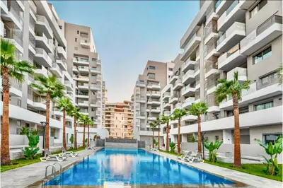 an apartment complex with a swimming pool and palm trees at Cocon Elégant CFC, Pool, Gym & Parking Gratuit in Oulad Akkou