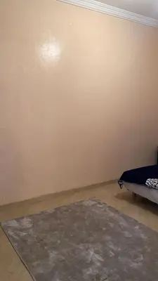 a room with a bed and a rug on a wall at Belle appartement et spacieuse in Meknès