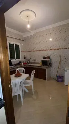 a kitchen with a table and two chairs and a table and a microwave at Belle appartement et spacieuse in Meknès