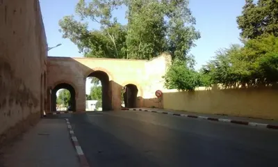 an empty road with a building and an archway at Belle appartement et spacieuse in Meknès