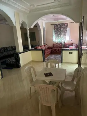 a living room with a table and chairs and a couch at Belle appartement et spacieuse in Meknès