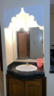 a bathroom with a sink and a large mirror at Belle appartement et spacieuse in Meknès
