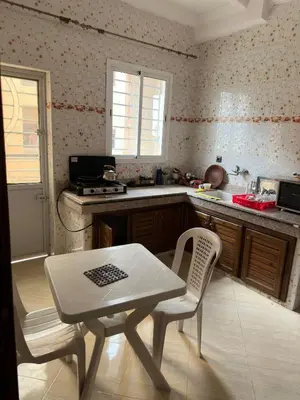 a kitchen with a table and a table and chairs at Belle appartement et spacieuse in Meknès