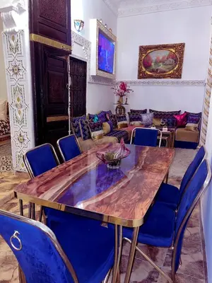 a dining room with a wooden table and blue chairs at Dar Noor Fès in Fès