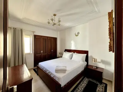 a bedroom with a bed and a chandelier at Chic & Spacious 4BR with Jacuzzi-Fez New City Stay in Fès