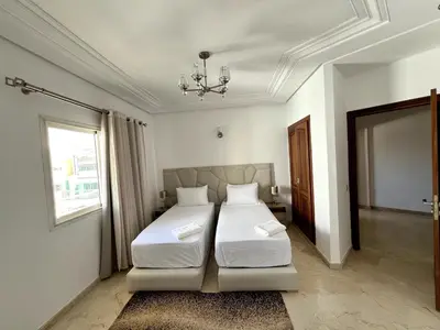 a bedroom with two beds and a chandelier at Chic & Spacious 4BR with Jacuzzi-Fez New City Stay in Fès