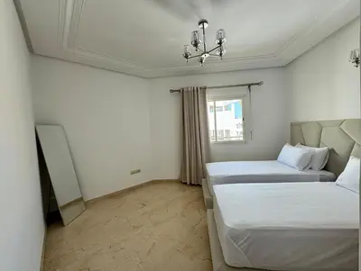 a bedroom with two beds and a chandelier at Chic & Spacious 4BR with Jacuzzi-Fez New City Stay in Fès
