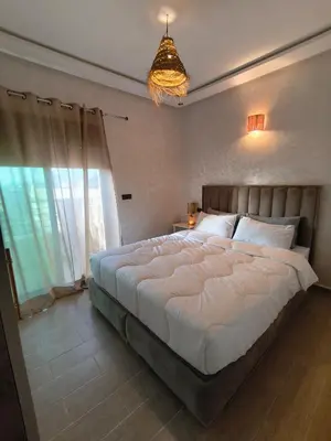 a bedroom with a large bed and a chandelier at prestige appartment in Fès