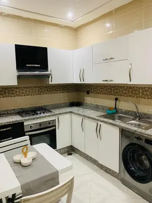 a kitchen with white cabinets and a sink and a table at prestige appartment in Fès