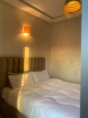 a bedroom with a white bed and two lights on the wall at prestige appartment in Fès
