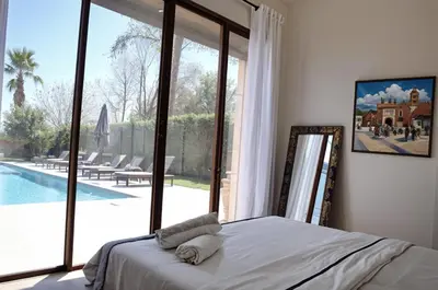 a bedroom with a bed and a view of a pool at Kridarek - Magnifique Villa avec piscine à Marrakech in Douar bel Rhanodour