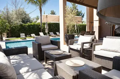 a patio with wicker chairs and tables next to a pool at Kridarek - Magnifique Villa avec piscine à Marrakech in Douar bel Rhanodour