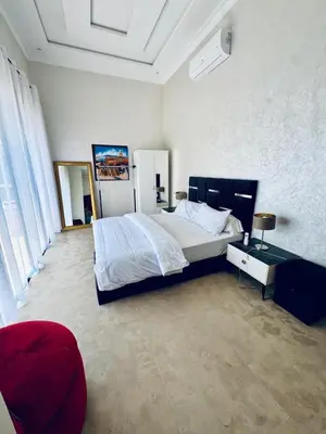a bedroom with a large bed and a red chair at Kridarek - Magnifique Villa avec piscine à Marrakech in Douar bel Rhanodour