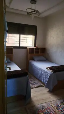 a bedroom with two beds and a window at Belle appartement in Meknès