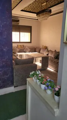 a living room with couches and flowers on a table at Belle appartement in Meknès