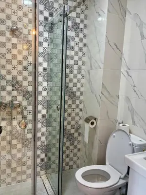 a bathroom with a toilet and a glass shower at Chic & Cozy Apartment in Tangier in Oulad Akkou