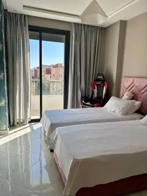 a bedroom with two beds and a chair with a window at Chic & Cozy Apartment in Tangier in Oulad Akkou