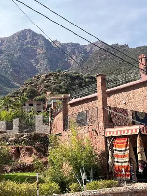 a brick building with mountains in the background at Ôtel Mrrakchi in Irghaf