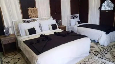 a bedroom with two beds with black and white pillows at Overnight luxury camp merzouga in Merzouga
