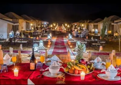 a table with plates of fruit and drinks and candles at Overnight luxury camp merzouga in Merzouga