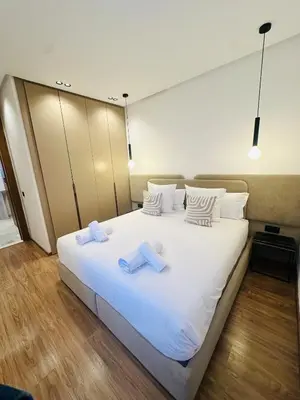 a large white bed with two towels on it at 1 Bedroom Apartment Rooftop Pool Marrakech in Oulad Akkou